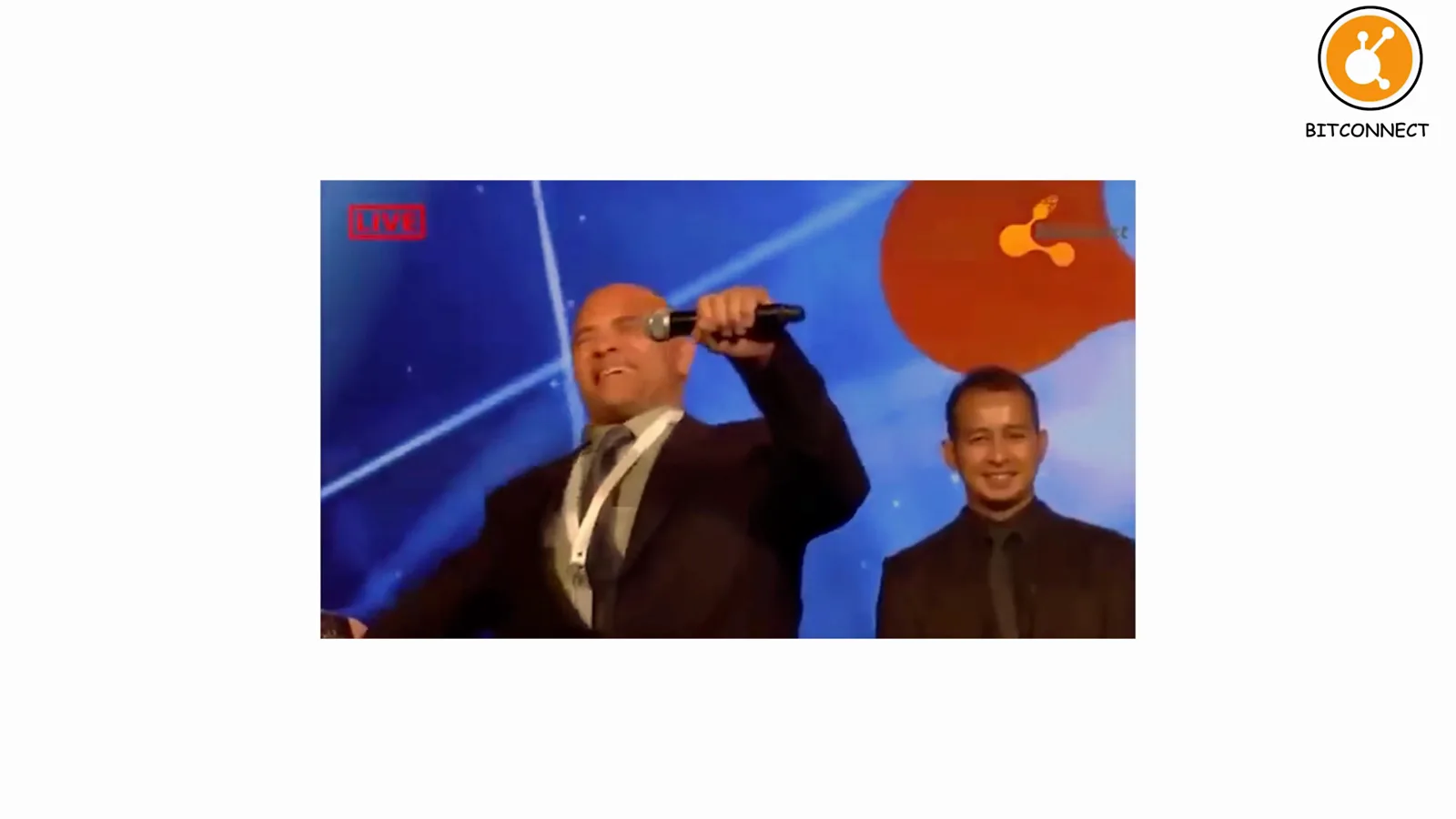 Carlos Matos shouting into a microphone on a blue conference stage, the viral BitConnect presentation that hyped the 1%-a-day Ponzi