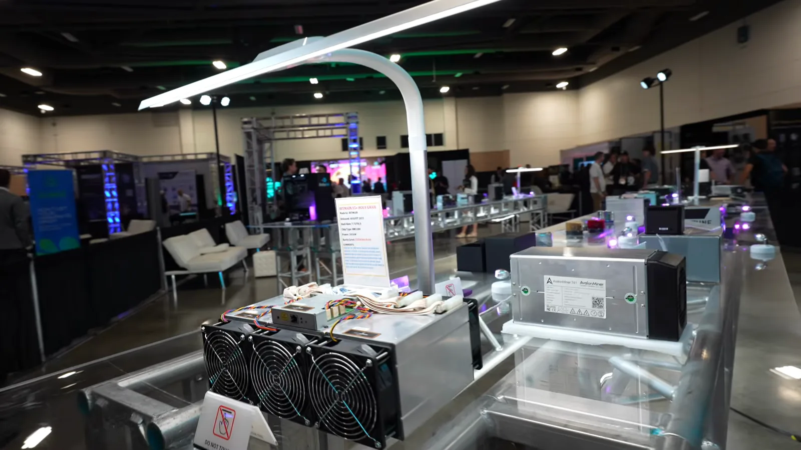 Wide view of the Bitcoin Mining Museum floor with rows of historic miners on glass display tables Wide view of the Bitcoin Mining Museum floor with rows of historic miners on glass display tables
