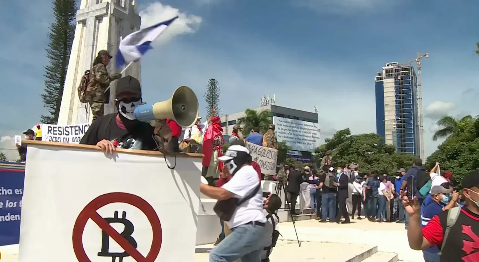 Protester waving a crossed-out bitcoin flag over an anti-bitcoin march through San Salvador against President Bukele's 2021 bitcoin law Protester waving a crossed-out bitcoin flag over an anti-bitcoin march through San Salvador against President Bukele's 2021 bitcoin law