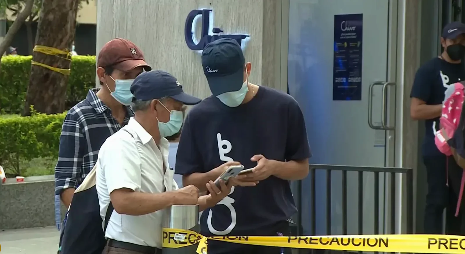 Two men checking a phone at a Chivo bitcoin ATM sealed with yellow PRECAUCION warning tape during the troubled September 7, 2021 launch day Two men checking a phone at a Chivo bitcoin ATM sealed with yellow PRECAUCION warning tape during the troubled September 7, 2021 launch day
