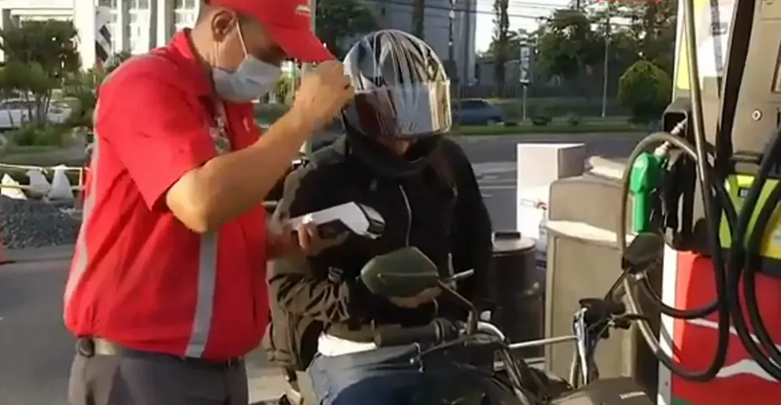 Gas station attendant in a red uniform taking payment from a helmeted motorcyclist at the pump, everyday dollar commerce that continued under El Salvador's bitcoin law Gas station attendant in a red uniform taking payment from a helmeted motorcyclist at the pump, everyday dollar commerce that continued under El Salvador's bitcoin law