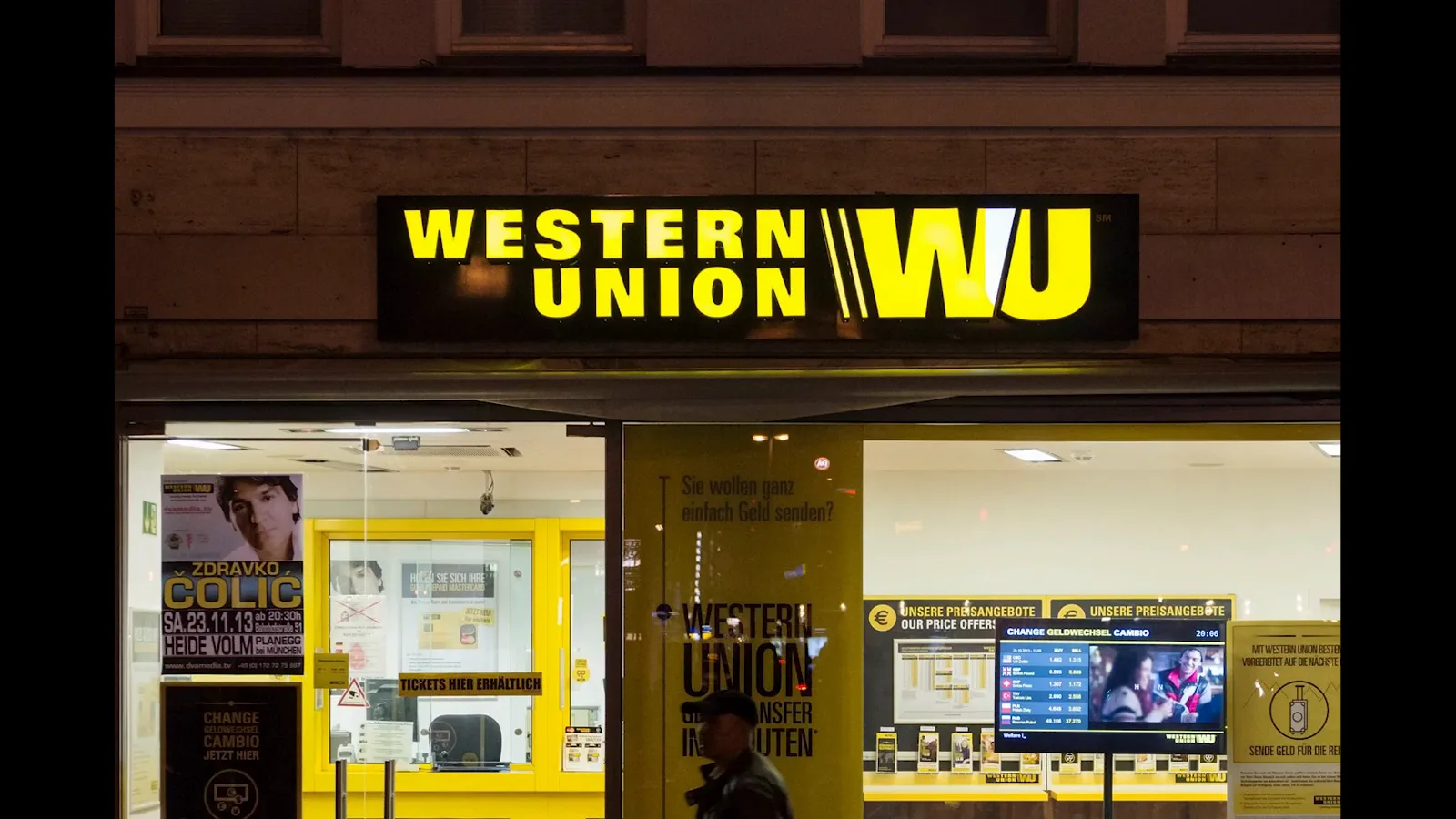 Western Union branch storefront glowing at night, the traditional fee-taking remittance channel Salvadoran migrants relied on before bitcoin transfers Western Union branch storefront glowing at night, the traditional fee-taking remittance channel Salvadoran migrants relied on before bitcoin transfers