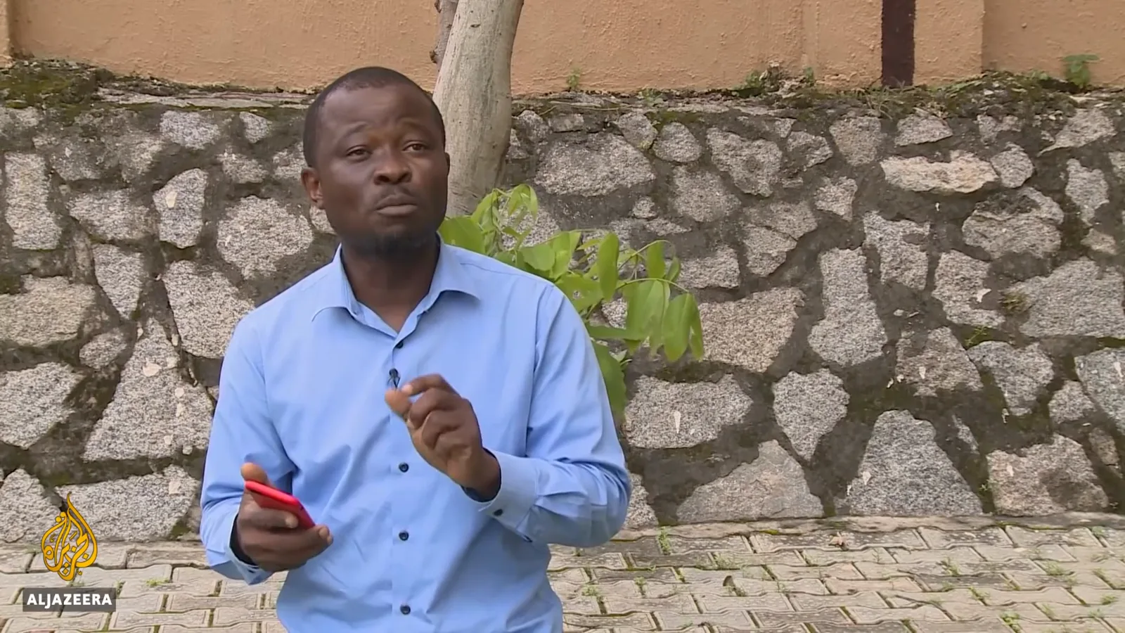 Nigerian early adopter holding his red-cased phone as he describes the eNaira app failing within an hour of the launch