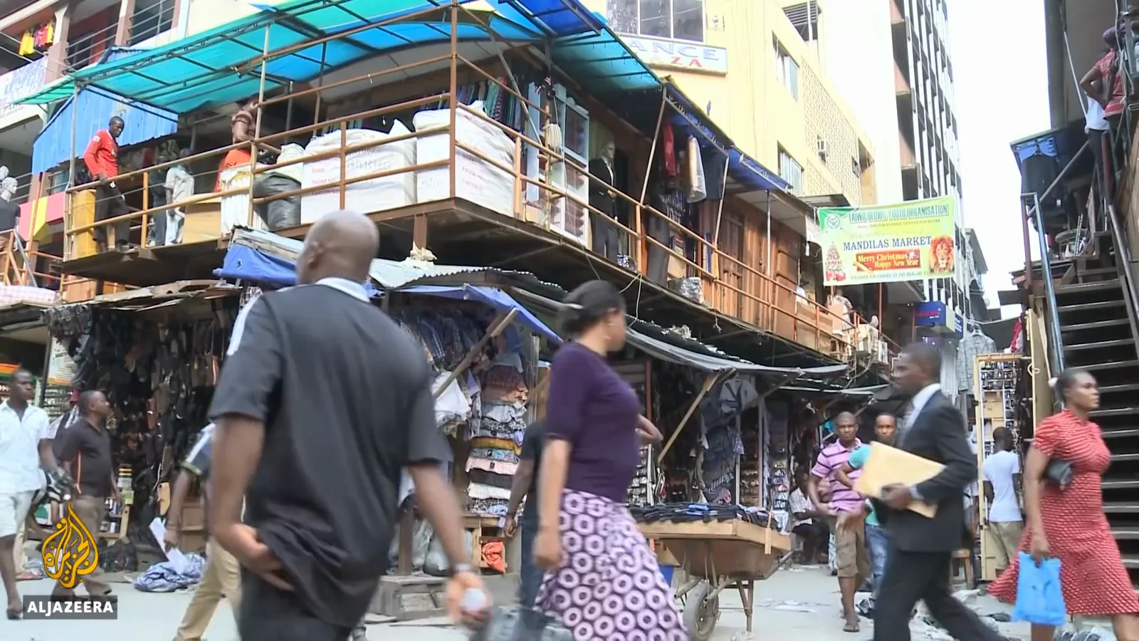 Shoppers walking through a dense Lagos street market where daily trade still runs almost entirely on cash