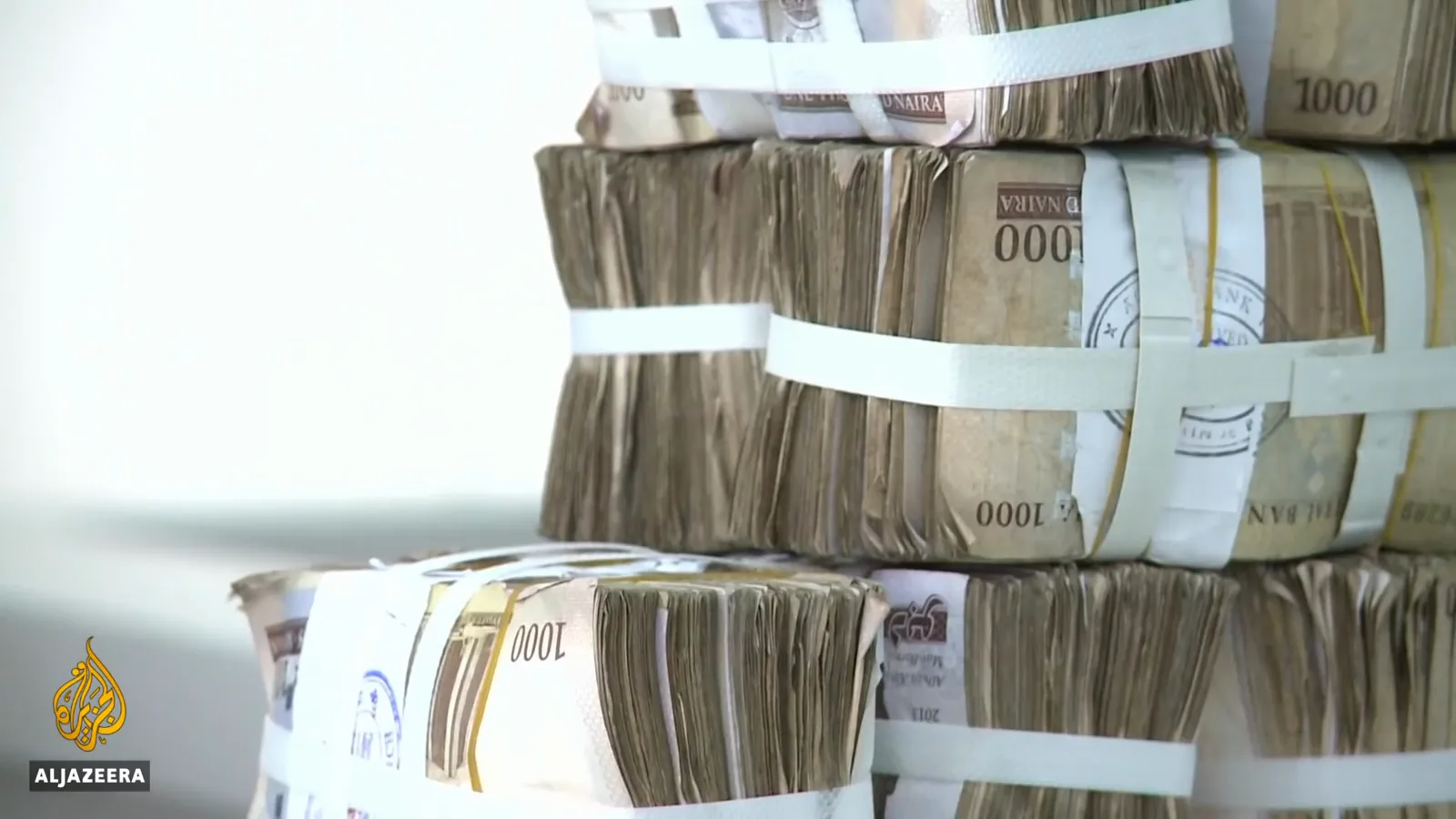 Brick-sized bundles of 1000-naira notes stacked at a Nigerian bank counter, the cash that eNaira failed to replace